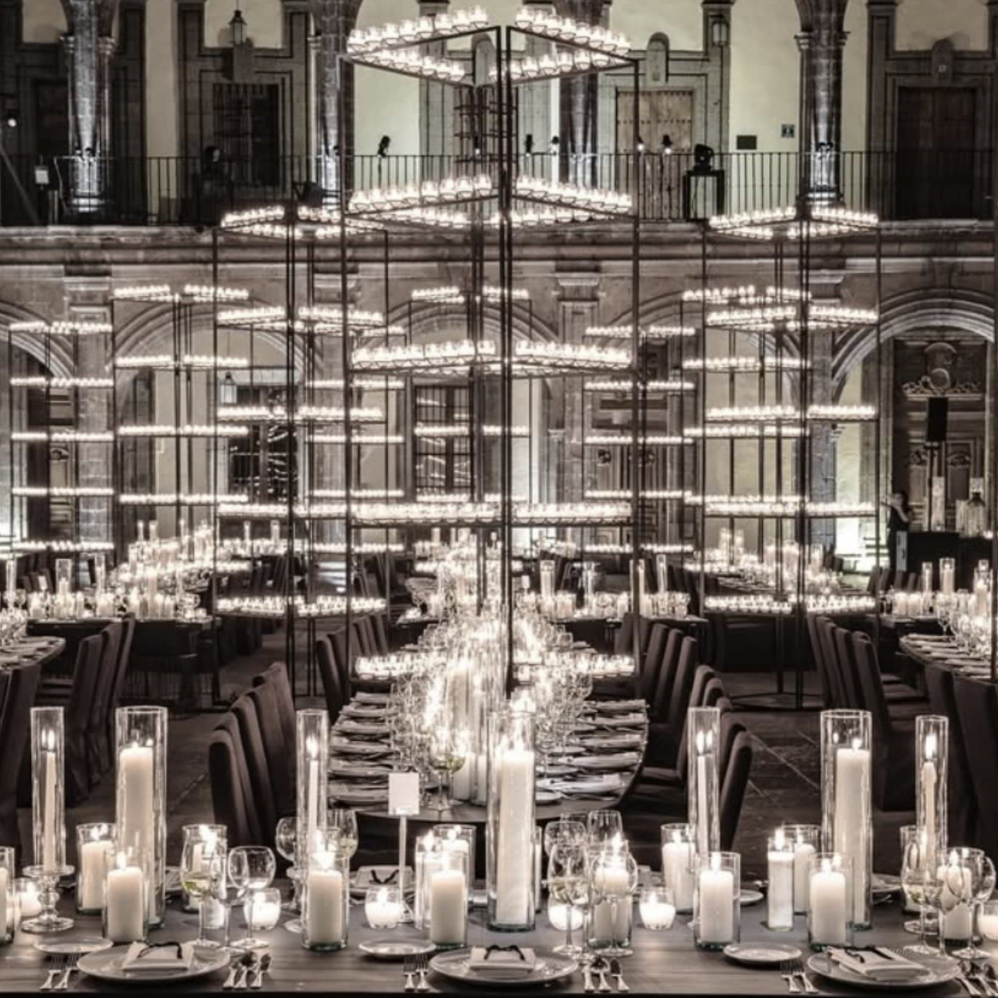 Banquete con cientos de velas y candelabros colgantes en el patio porticado de un edificio colonial